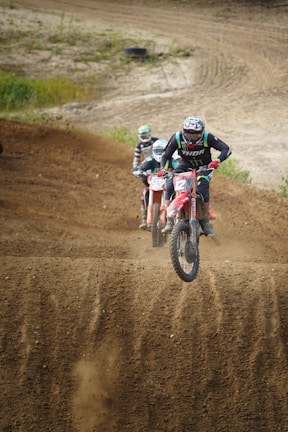 A group of dirt bike riders racing on a rugged outdoor track.