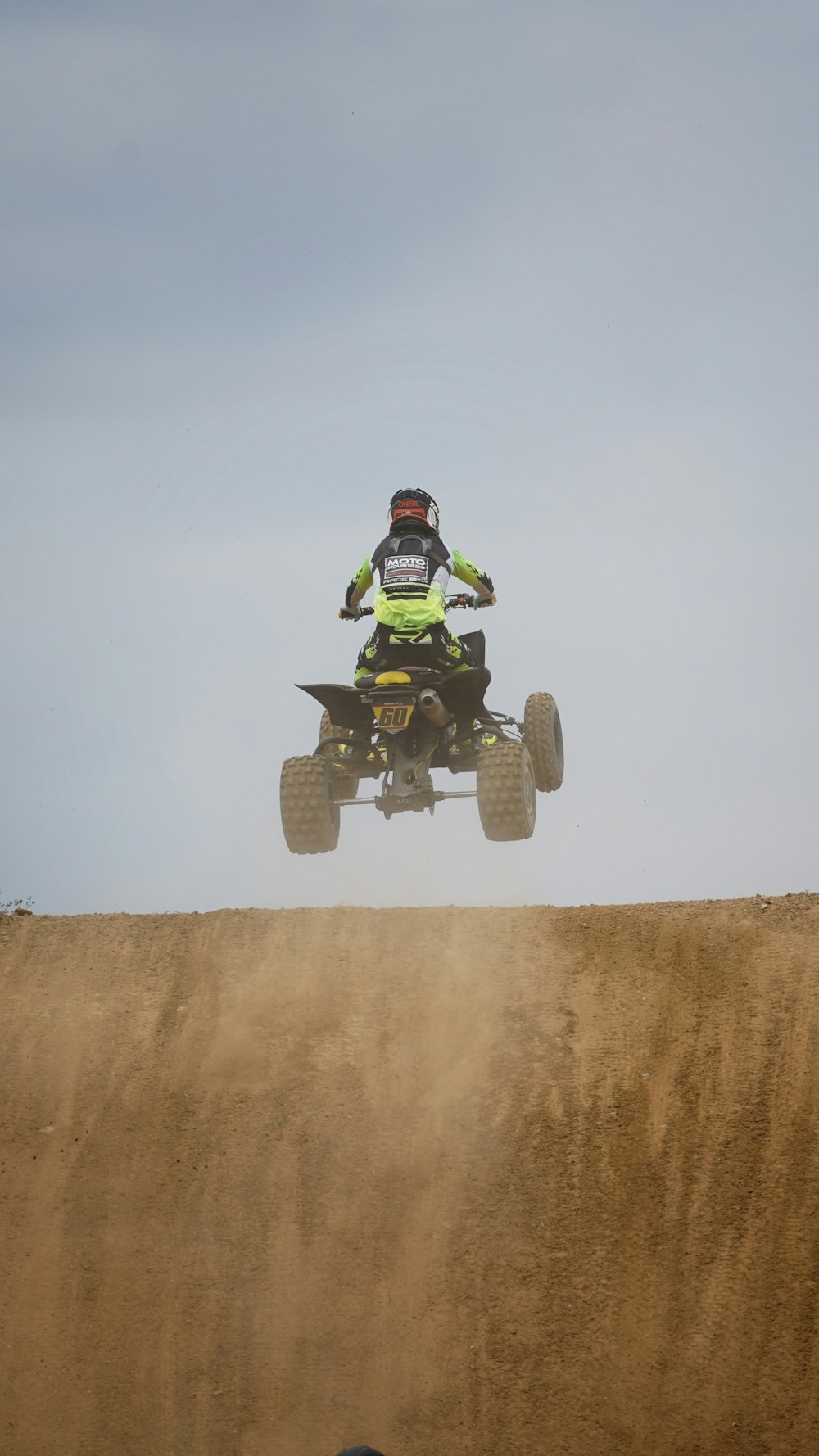 um homem andando de quatro rodas no topo de uma colina de terra