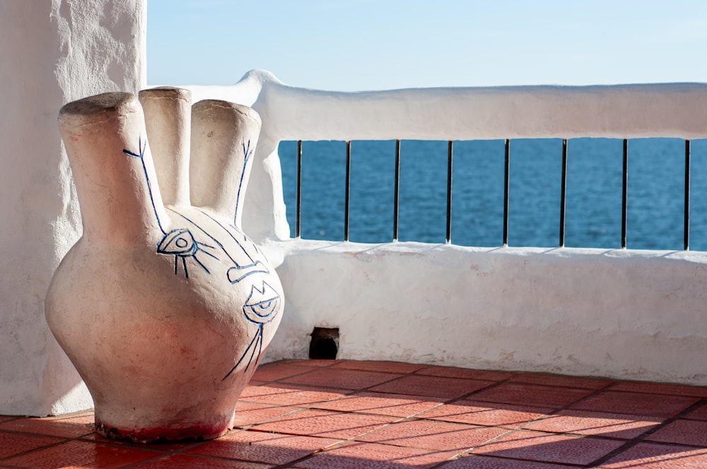 a white vase sitting on top of a brick floor