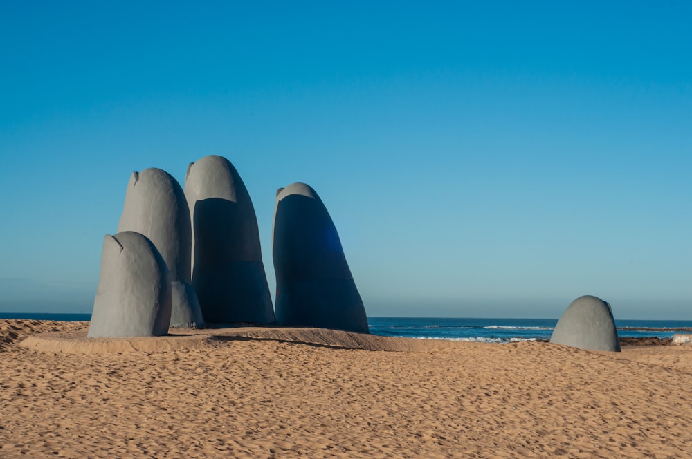 Ein Sandstrand mit einer Gruppe von großen Felsen, die aus dem Sand ragen
