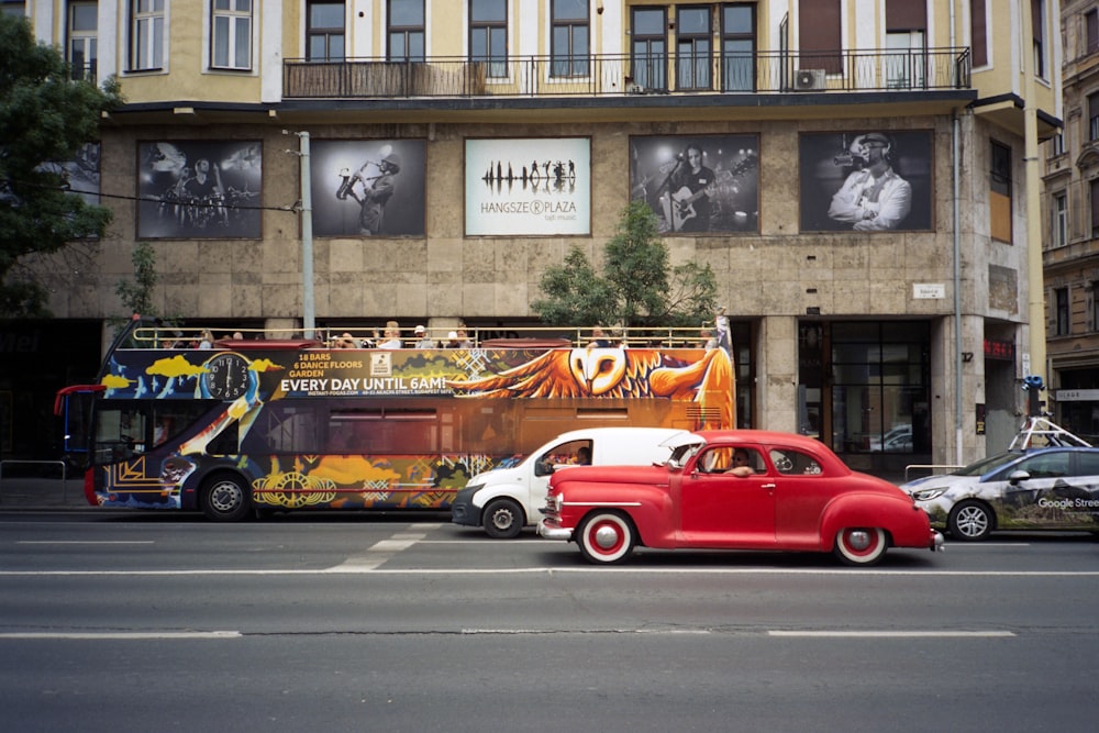 a red car driving down a street next to a tall building