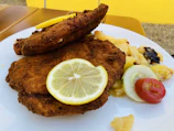 Close-up of a hearty Wiener Schnitzel with lemon wedge and parsley garnish on a ceramic plate