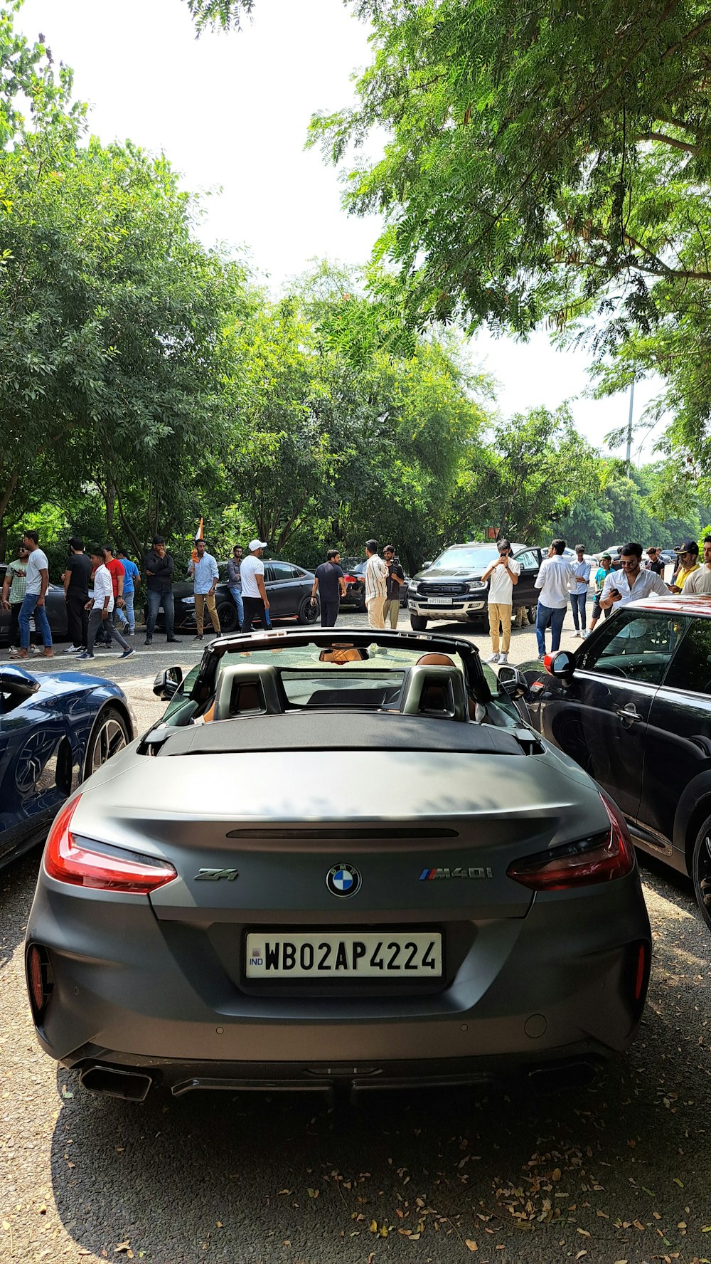 a group of people standing around parked cars