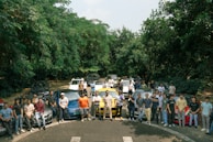 A group of smiling drivers standing together in front of their cars, showing camaraderie.