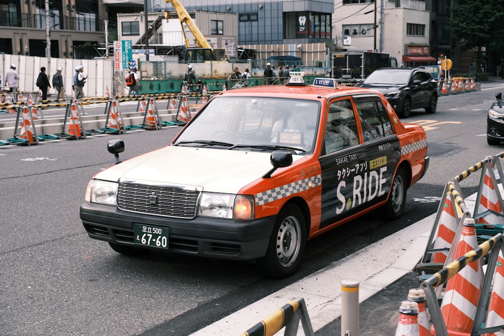 Un coche de policía naranja y blanco conduciendo por una calle