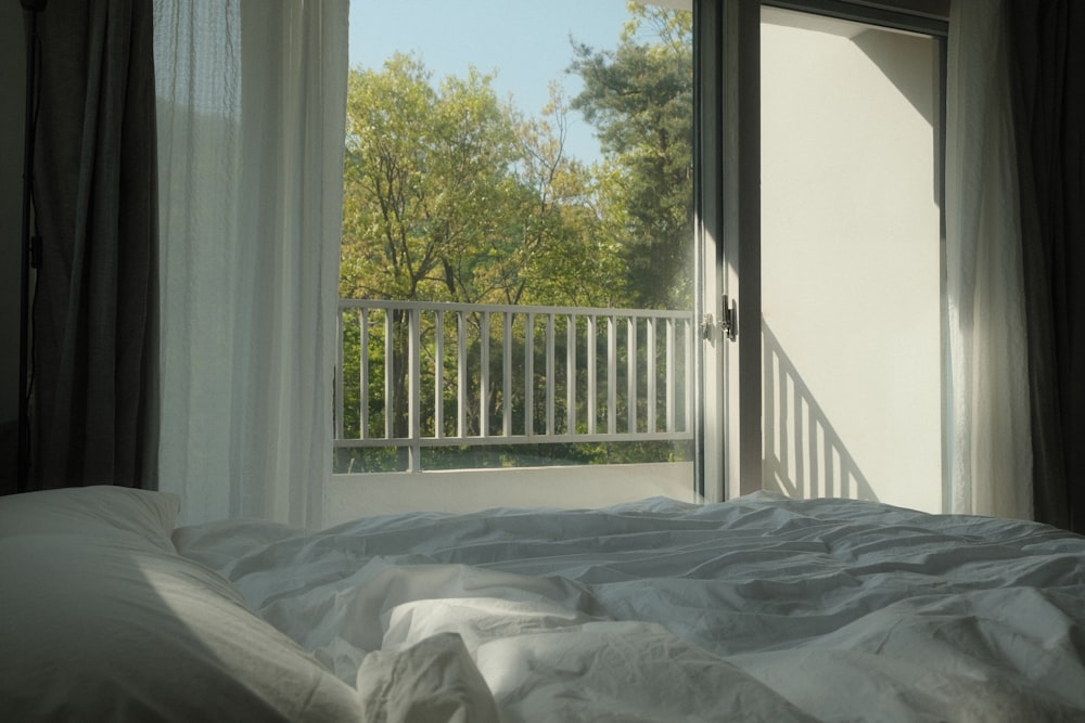 a bed with a white comforter and a balcony