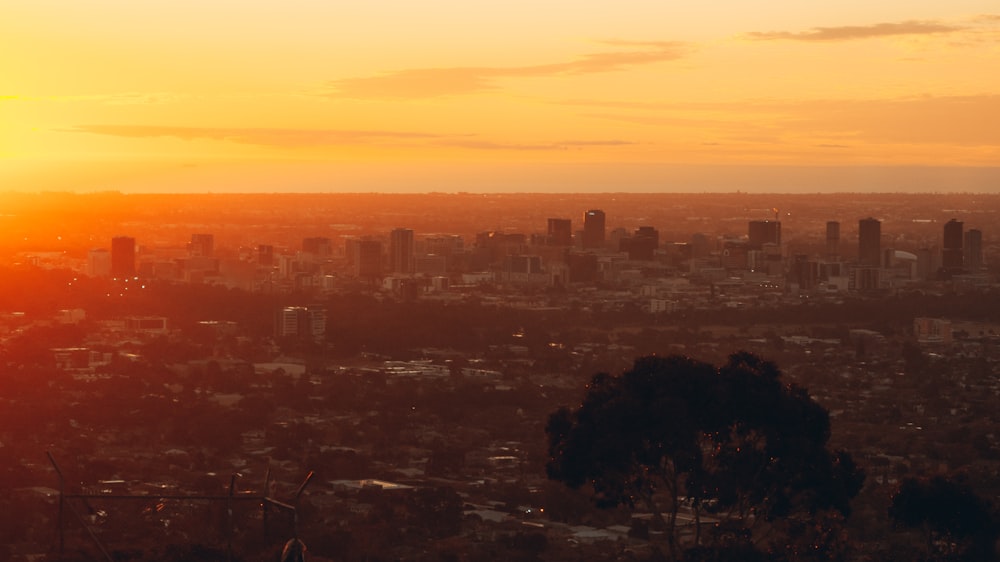 the sun is setting over a city with tall buildings