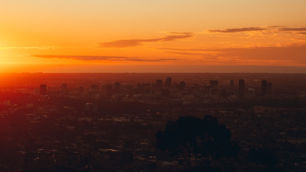 the sun is setting over a city with tall buildings