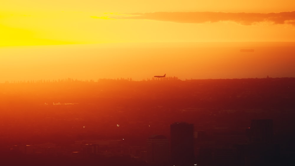 Ein Flugzeug fliegt bei Sonnenuntergang über eine Stadt