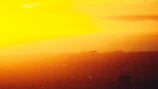 An airplane soaring above clouds during a sunset over the USA.