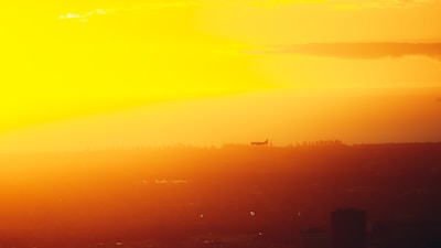Airplane flying over a scenic landscape at sunset.