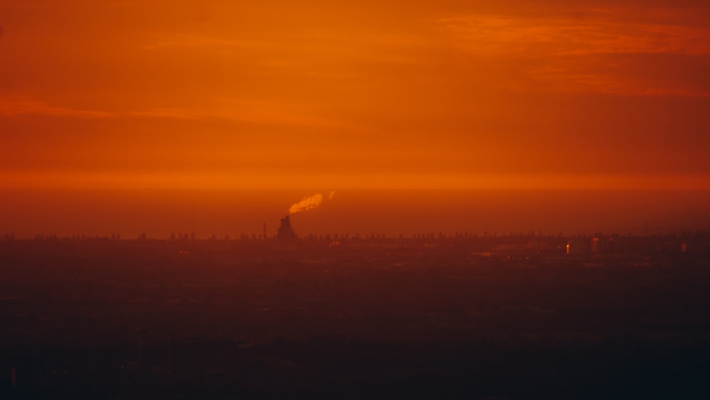 a red sky with a smokestack in the distance