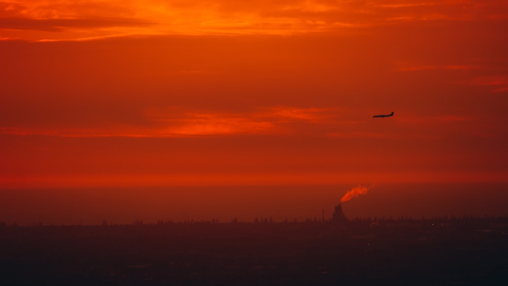 a plane flying in the sky at sunset