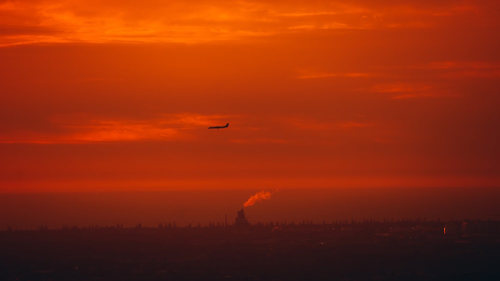 a plane flying in the sky at sunset