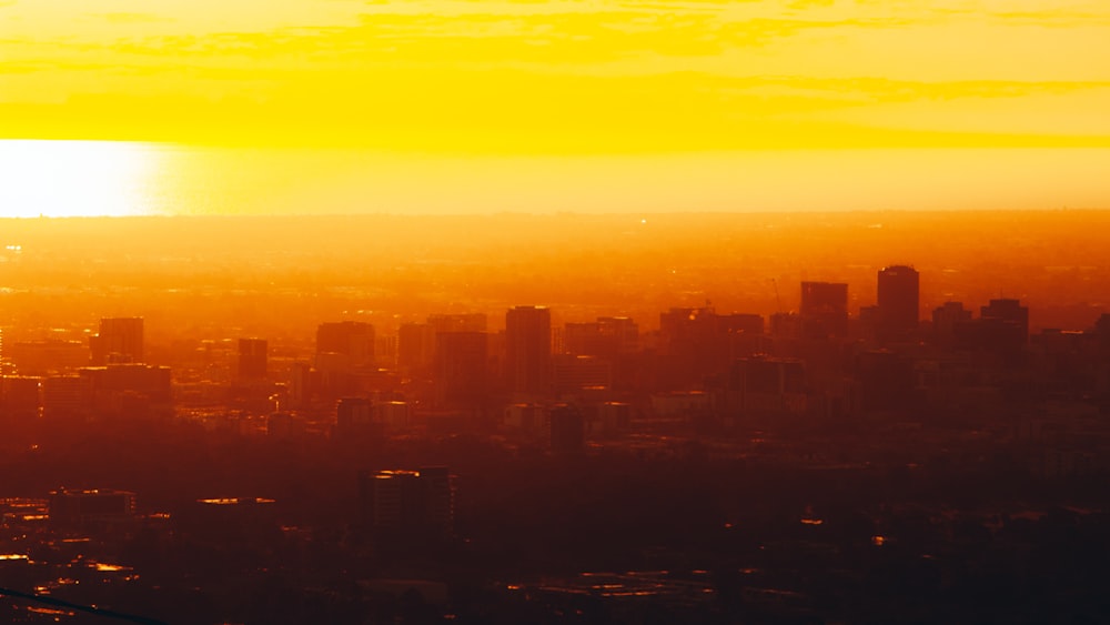 the sun is setting over a city with tall buildings