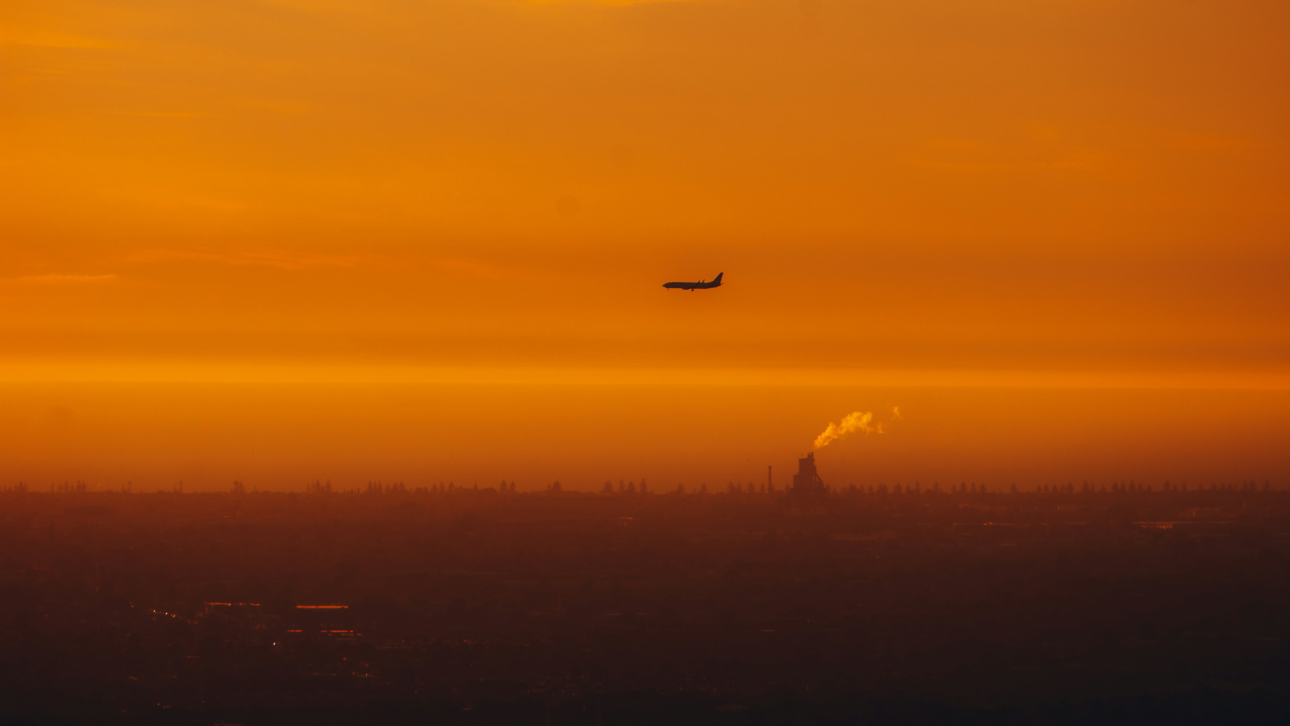 a plane flying over a city at sunset