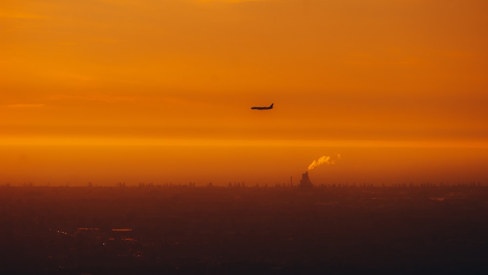 a plane flying over a city at sunset