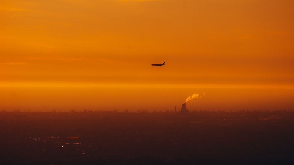 Ein Flugzeug, das bei Sonnenuntergang über eine Stadt fliegt