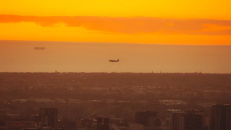 A vibrant photo of Madrid's skyline at sunset with an airplane soaring above, symbolizing international travel.
