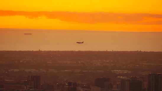 A vibrant photo of Madrid's skyline at sunset with an airplane soaring above, symbolizing international travel.