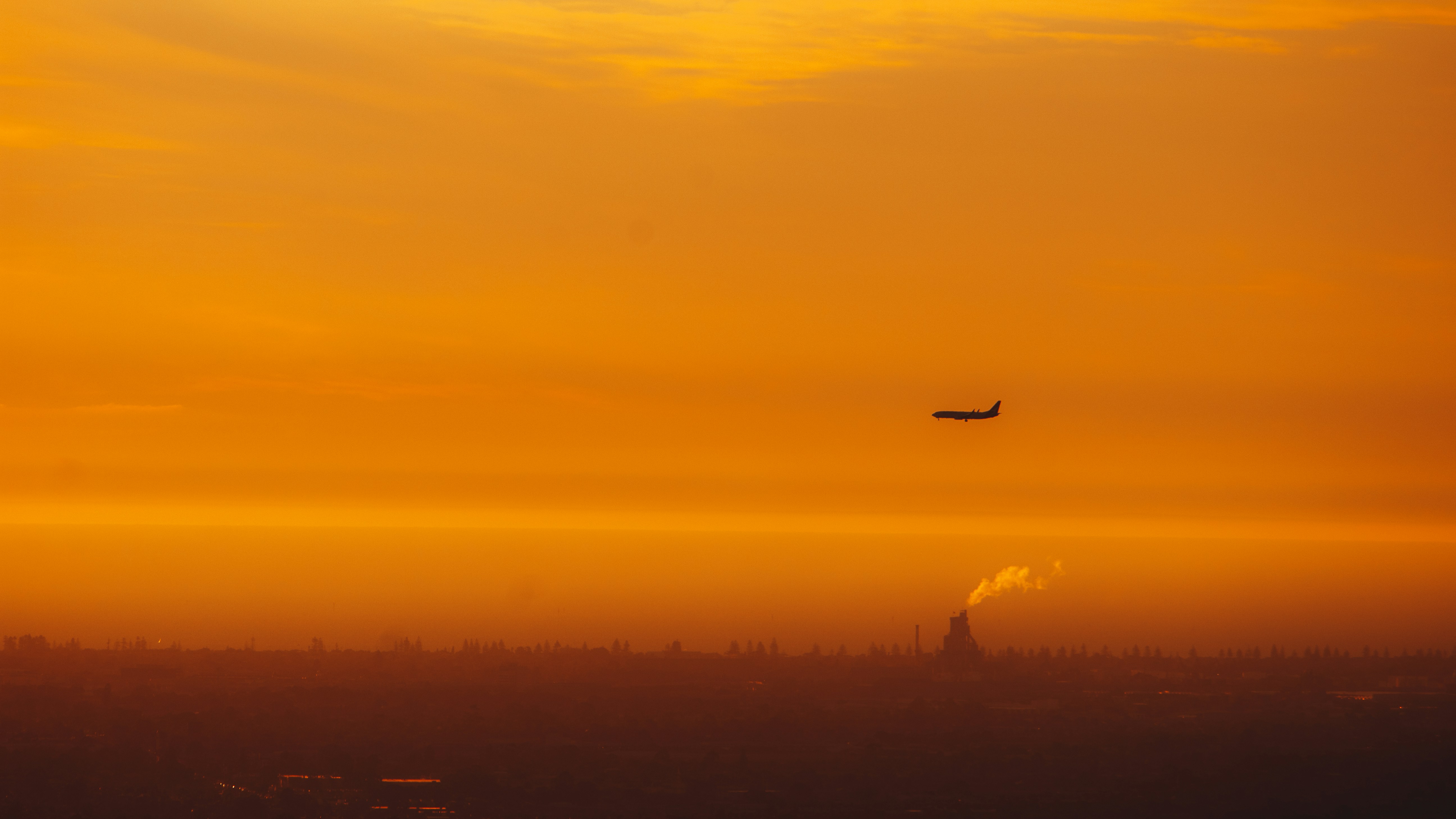 a plane flying in the sky at sunset, 