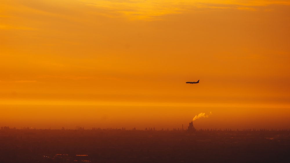 a plane flying in the sky at sunset