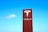 A large red sign with the Tesla logo and brand name against a clear blue sky.