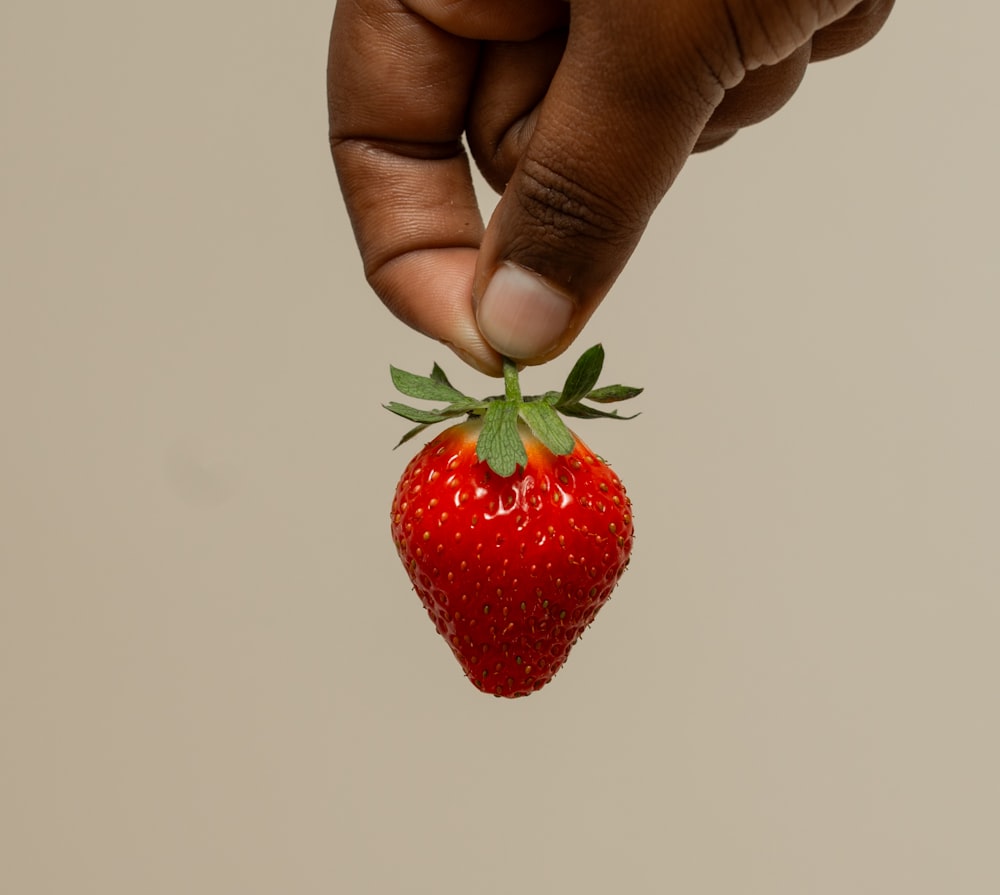 a person holding a strawberry in their hand