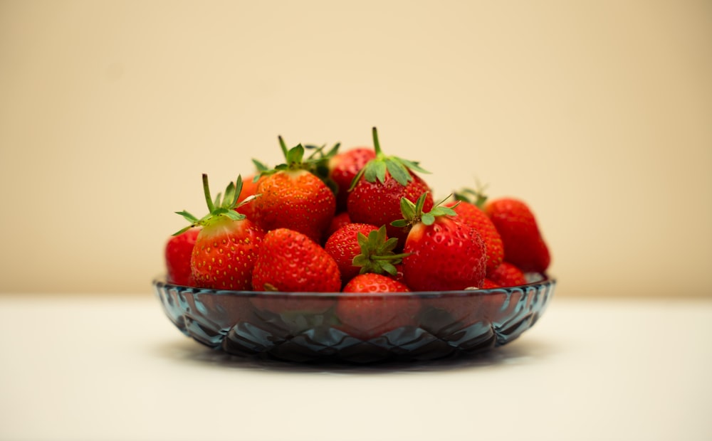 a glass bowl filled with lots of ripe strawberries
