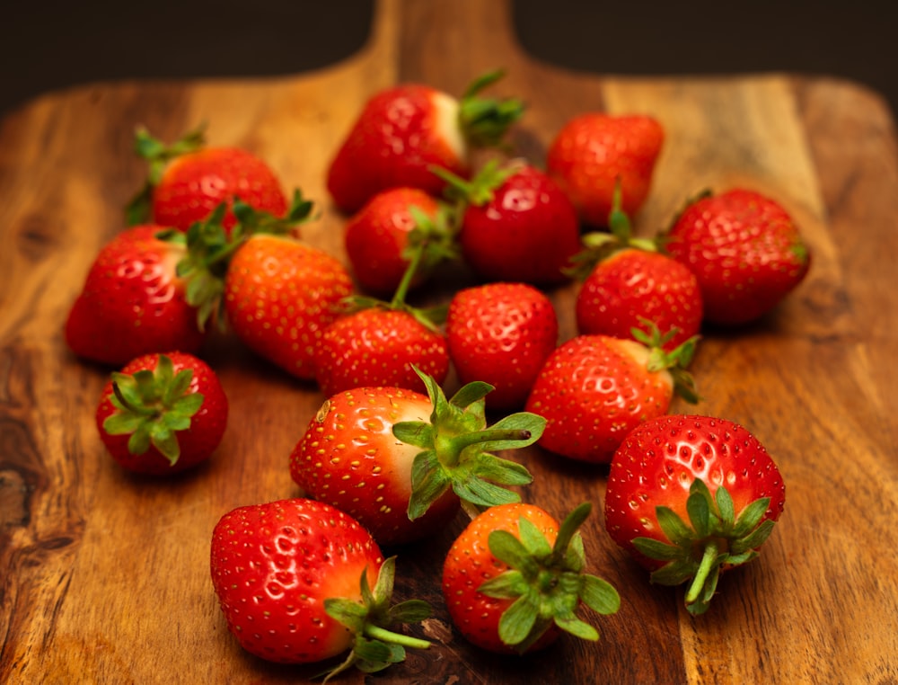 a wooden cutting board with a bunch of strawberries on it