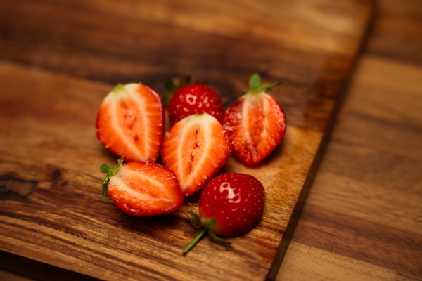 Bright red strawberries arranged on a rustic wooden board, some dipped in white chocolate.