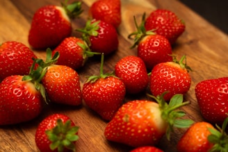 Bright red frozen strawberries scattered on a wooden surface.