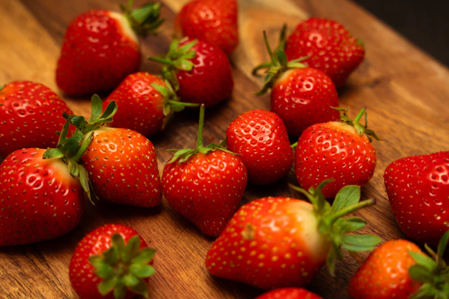 Close-up of fresh, ripe strawberries glistening with morning dew on a rustic wooden table.