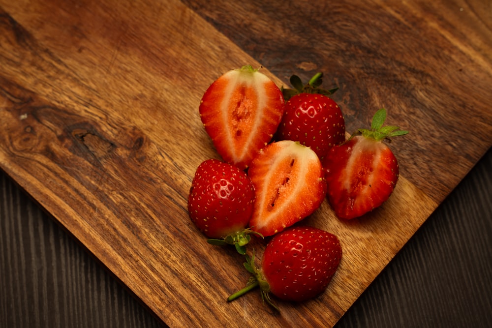 four strawberries on a cutting board on a table
