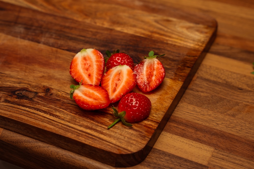 a wooden cutting board topped with sliced strawberries