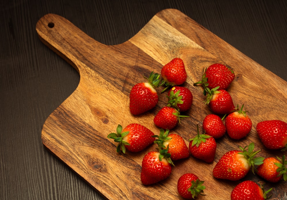 a cutting board with a bunch of strawberries on it