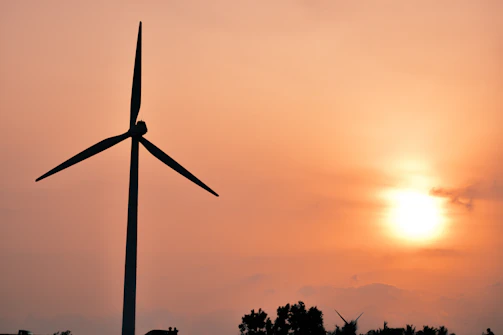 Engineers working on a large wind turbine base during sunset.
