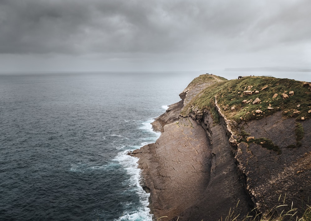 a rocky cliff with a body of water in the background