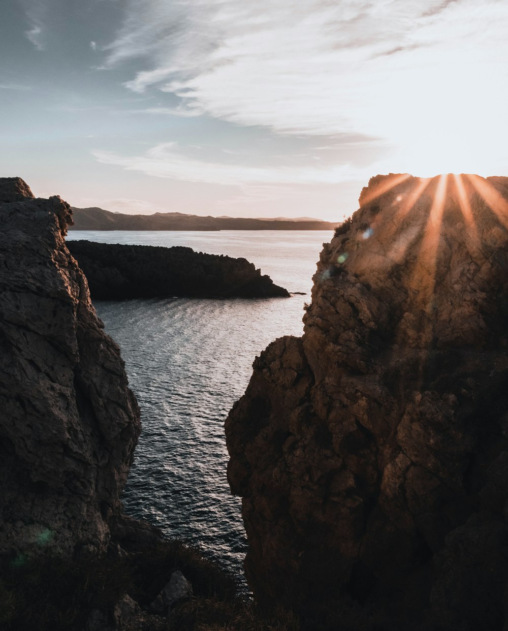 the sun is shining over the water from a cliff