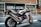 A sleek Honda motorcycle is parked on an urban street. The design of the motorcycle features a sporty build with a color scheme of white, red, and blue. It is positioned in front of a modern building with large windows and decorative patterns.