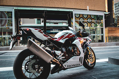 A sleek modern Honda motorcycle parked on a city street at sunset.