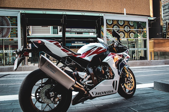 A sleek red Honda motorcycle parked in front of the Honda Santa Fé dealership in a sunny Colombian street.