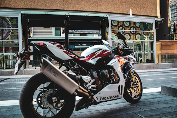 A sleek red Honda sport motorcycle parked on a city street at sunset.