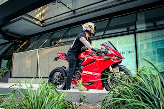 Close-up of a happy customer wearing a helmet, sitting on a stylish Piaggio motorcycle under bright sunlight.