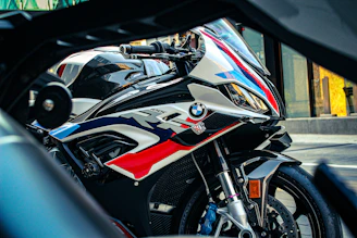 A sleek BMW R1000 racing down a sunlit highway, the rider leaning into a sharp curve.