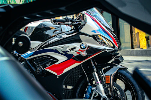 A sleek BMW R1000 racing down a sunlit highway, the rider leaning into a sharp curve.