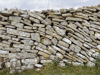 A small decorative dry stone wall bordering a flower bed in a garden.