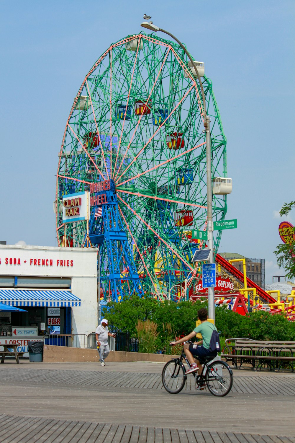 a man riding a bike next to a ferris wheel