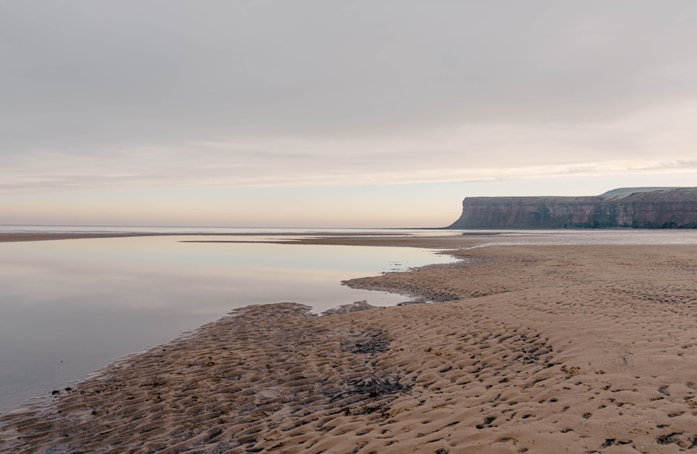 a body of water sitting on top of a sandy beach