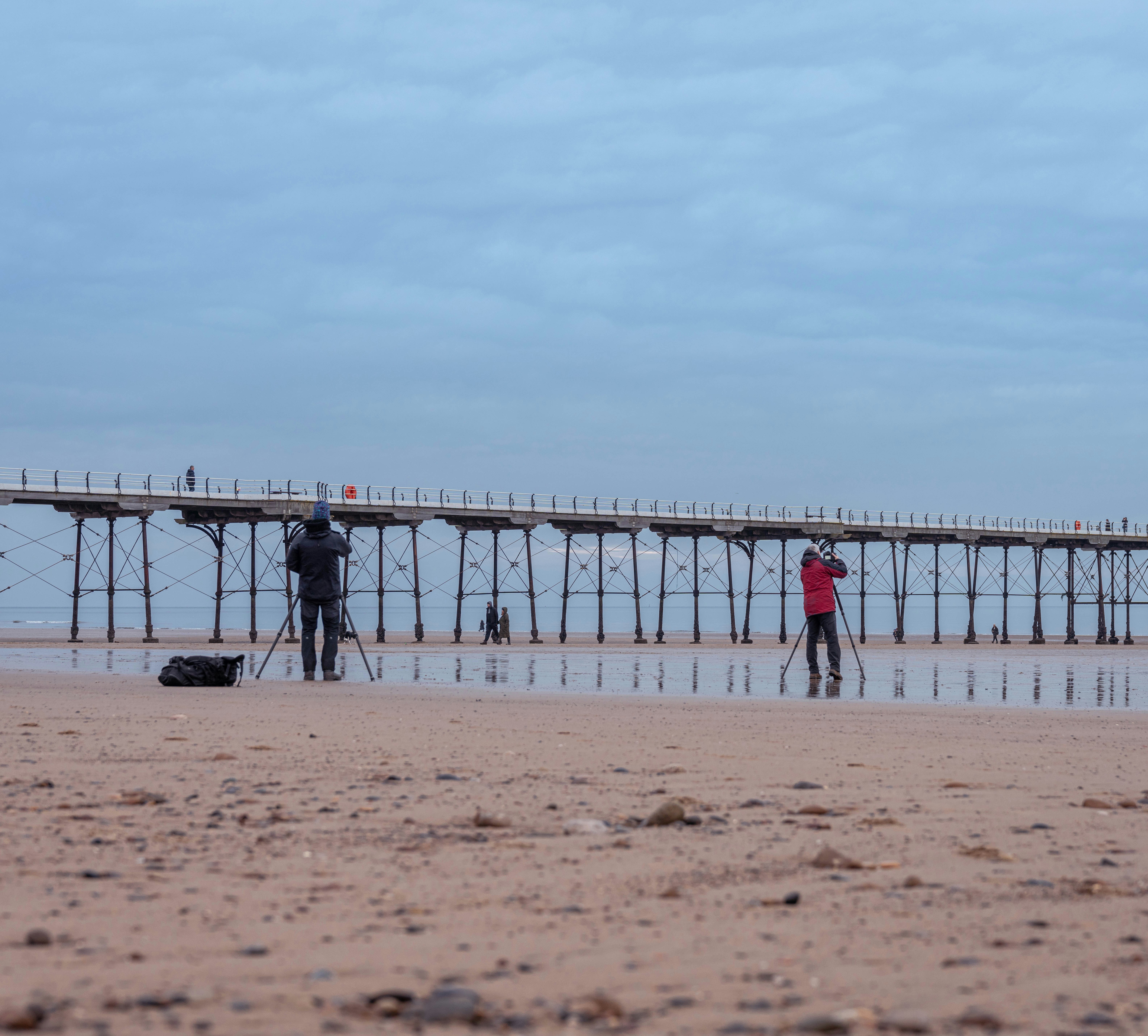 a couple of people standing on top of a sandy beach
